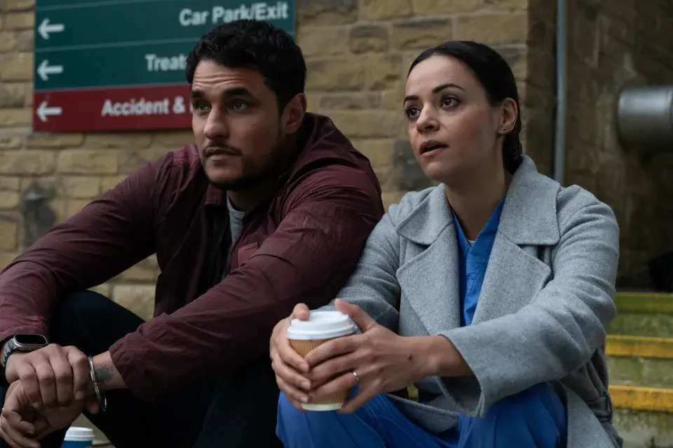 Detective Harry Virdee sitting on hospital steps talking with Saima in BBC’s Virdee series
